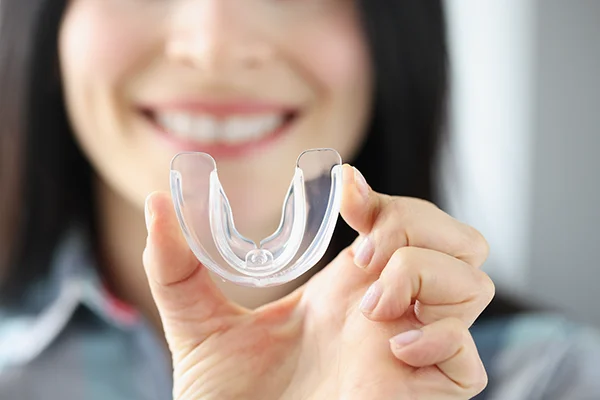 Close up of a simple mouthguard being held up by an excited woman at Lakeview Dental Center 