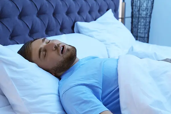 Man with sleep apnea snoring while trying to sleep in bed.