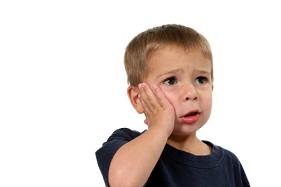 Little boy with a toothache holding his hand over his face